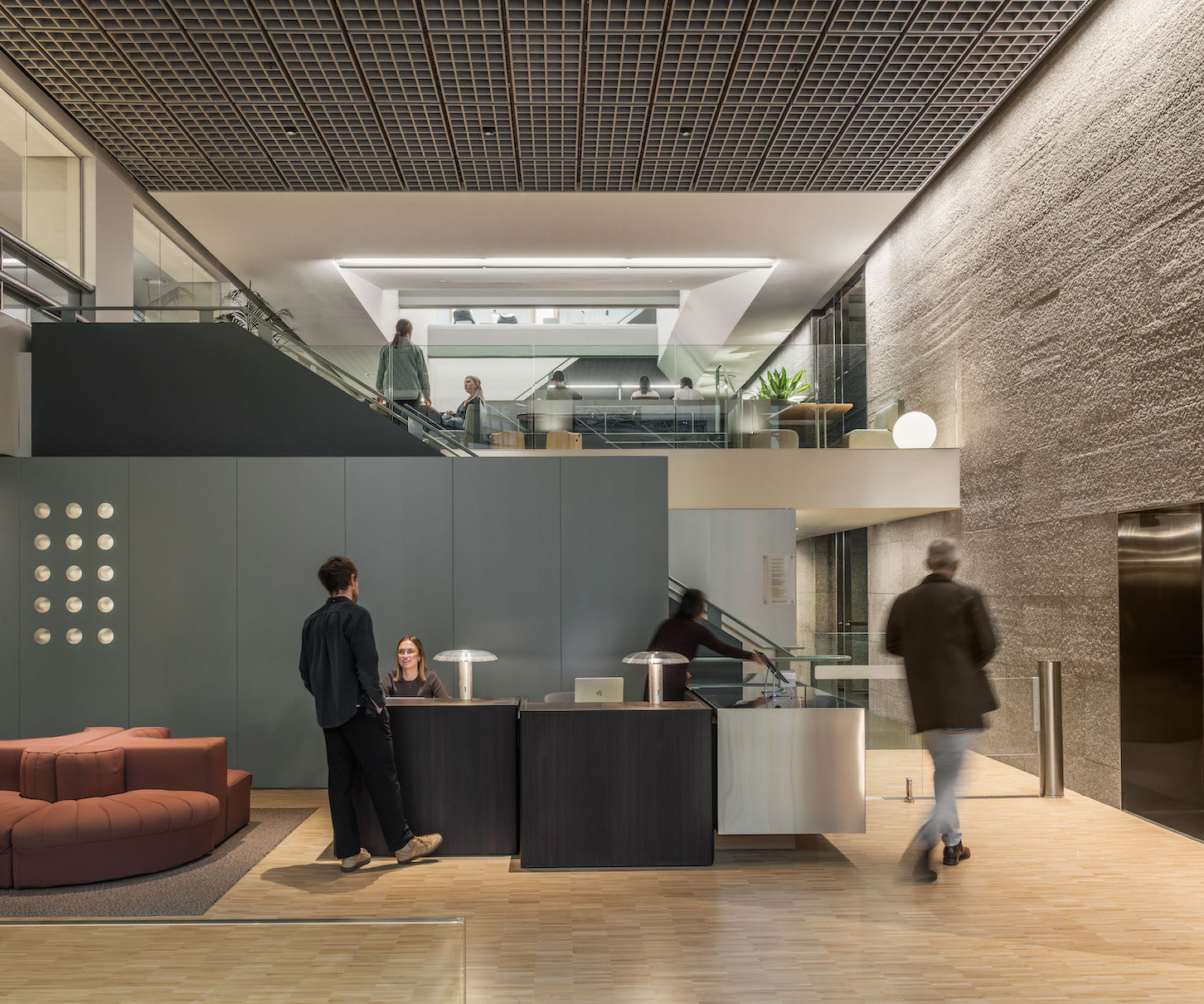 A modern office reception with a mezzanine workspace and people meeting