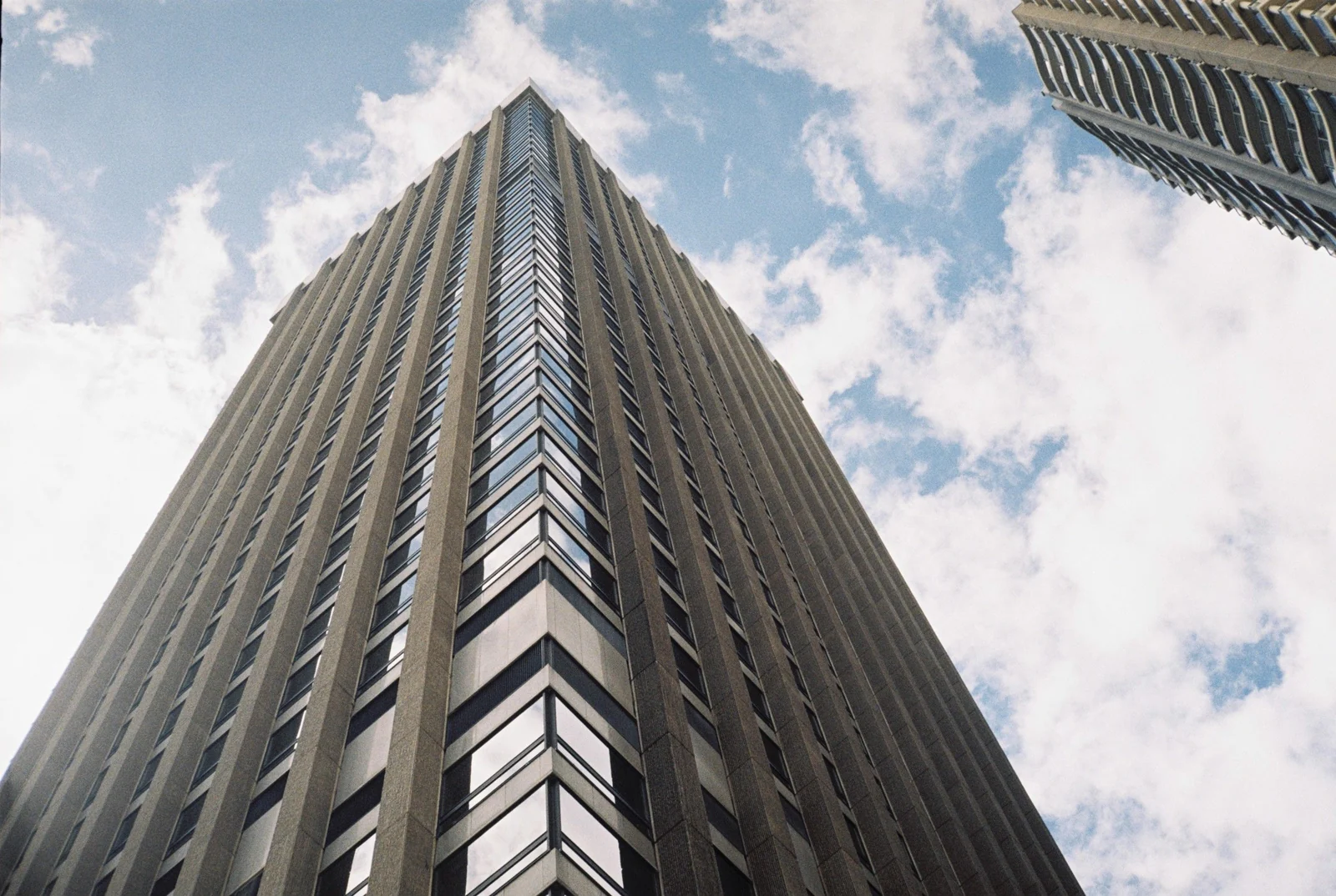 Low-angle view of a commercial office building against a partly cloudy sky