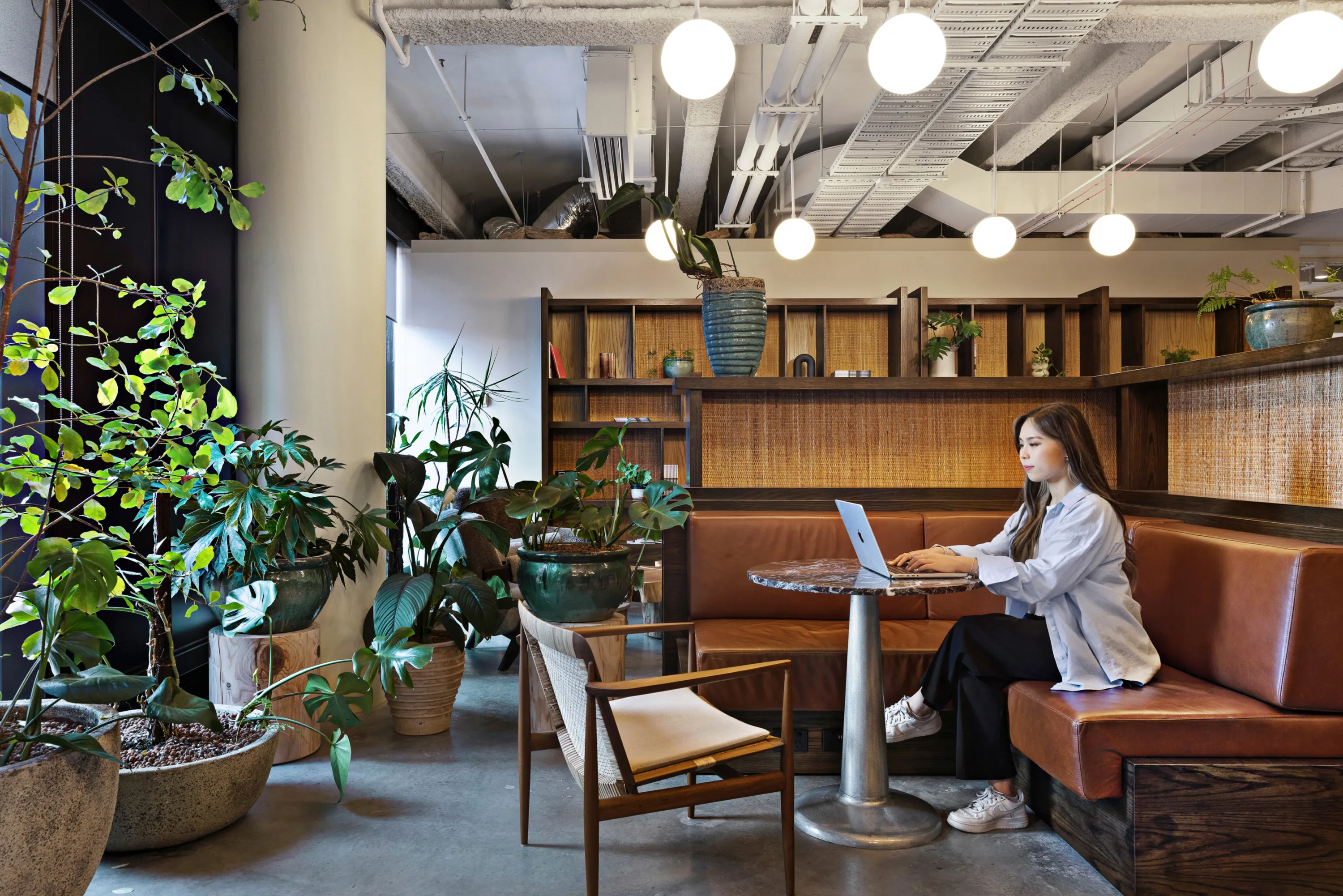 A professional working on her laptop in a bright shared workspace